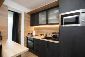 una cucina con armadi neri e forno a microonde di Gyopárosi Deluxe Private Wellness House 4 Csillag a Orosháza Altre 8 foto