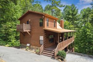 a log cabin in the woods with a balcony at Beautiful Escape by American Patriot Getaways in Cove Creek Cascades
