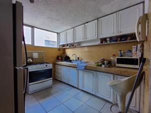 a kitchen with white cabinets and a sink and a stove at Edificio Foch in Quito