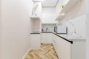 a white kitchen with white cabinets and a microwave at Buhar Zhyray Exclusive-1 in Zhezdi