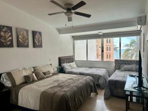 a bedroom with two beds and a ceiling fan at 2 bdrm - Sleeps 8 -Ocean front -Ocean View in Mazatlán