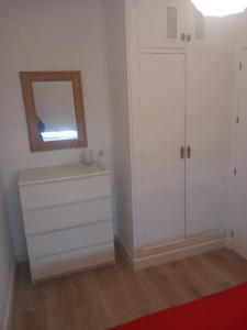 biała sypialnia z lustrem i komodą w obiekcie Apartamento Valdelagrana w mieście El Puerto de Santa María +25 zdjęć