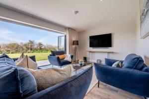 a living room with blue furniture and a large window at Fair Skies in St Merryn