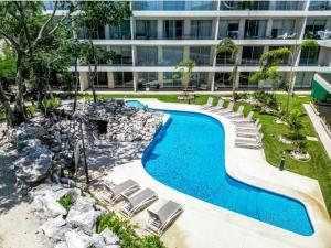 ein Swimmingpool mit Stühlen und einem Gebäude in der Unterkunft Departamento en zona exclusiva a minutos de la playa y de la 5ta Av in Playa del Carmen