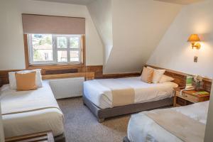 a hotel room with two beds and a window at Hotel Museo El Greco Puerto Varas in Puerto Varas