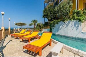a row of yellow benches next to a swimming pool at Yellow villa in Gonio in Gonio