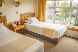 a hotel room with two beds and a window at Hotel Museo El Greco Puerto Varas in Puerto Varas