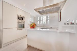 a kitchen with white cabinets and a bowl of fruit on the counter at The Sandbox in Saundersfoot