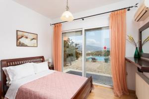 a bedroom with a bed and a sliding glass door at Villa Glan Y Mor in Elounda +111 photos