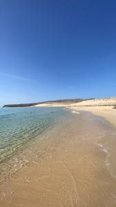 a beach with the ocean and a blue sky at La Lajita Vacation Home in Pájara +4 photos