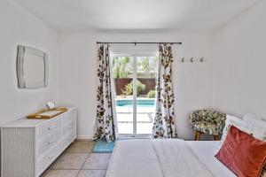 ein Schlafzimmer mit einem Bett und ein Fenster mit einem Pool in der Unterkunft Cozy Desert Bungalow in Palm Springs