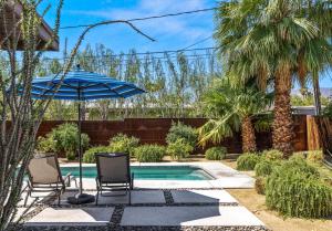 ein Swimmingpool mit zwei Stühlen und einem Sonnenschirm in der Unterkunft Cozy Desert Bungalow in Palm Springs + 14 Fotos