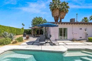 ein Haus mit Swimmingpool und Sonnenschirm in der Unterkunft Cozy Desert Bungalow in Palm Springs