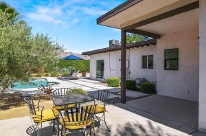 eine Terrasse mit Tisch und Stühlen und einem Pool in der Unterkunft Cozy Desert Bungalow in Palm Springs