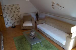 una sala de estar con un sofá y una silla en Ferienwohnung Schöne Aussicht, en Bad Marienberg