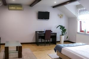 a bedroom with a desk and a bed and a tv at Pokoje De Luxe Figaro in Płock