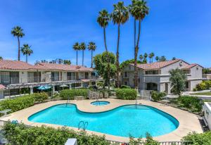 an image of a swimming pool at a resort with palm trees at Cozy Ranch-Style Condo in Palm Springs