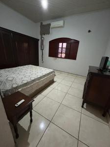 a bedroom with a bed and a table and a window at Apartamento no centro in Presidente Venceslau
