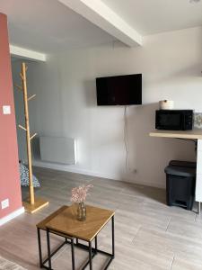 sala de estar con mesa de centro y TV en Studio de la Baroud Family, en La Pommeraye