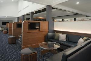 a waiting room with a couch and a tv at Courtyard by Marriott Louisville East in Louisville
