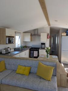 a living room with a couch and a kitchen at Seascape Caravan in Kinmel Bay