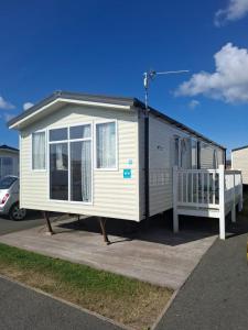 a white tiny house with a porch on a parking lot at Seascape Caravan in Kinmel Bay