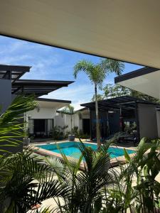 a swimming pool with palm trees in front of a house at Jardín de Martín - Hotel Boutique in Puerto Jiménez