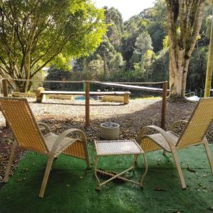 twee stoelen en een tafel met een pot erop bij SUITES - Românticas na natureza para adultos in Itapecerica da Serra