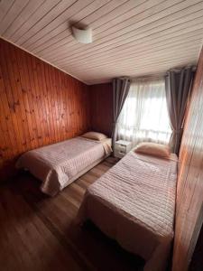 une chambre avec deux lits et une fenêtre dans l'établissement Casa Luma, à Puerto Montt