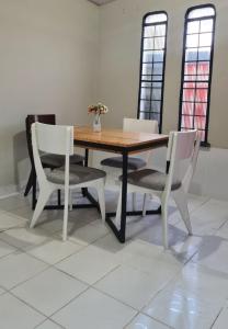 a wooden table with two white chairs and a table with flowers on it at Apartamento no centro de Boa Vista in Boa Vista