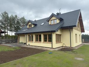 a house with a black roof on a yard at Sielski Dom in Suwałki