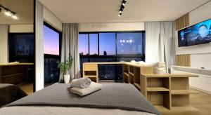 een slaapkamer met een bed, een tv en ramen bij CURTA! |165| Lindo Studio | Próx Centro de Eventos in Balneário Camboriú