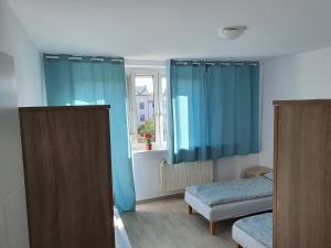 a room with two beds and a window with blue curtains at Hostel Berberysowa in Wrocław