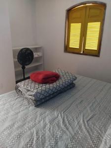een bed met daarop een rood kussen bij Casa para alugar in Paraty