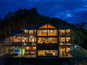 ein großes Haus mit vielen Fenstern in der Nacht in der Unterkunft Skyfall Lodge by American Patriot Getaways in Park Settlement