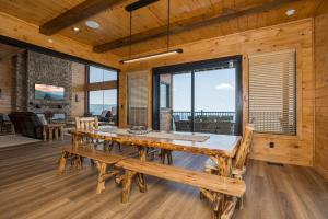 ein Esszimmer mit einem großen Holztisch und Bänken in der Unterkunft Skyfall Lodge by American Patriot Getaways in Park Settlement