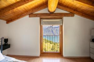 a bedroom with a window with a mountain view at L'angolo di Fonteno in Fonteno