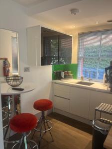 オックスフォードにあるOxford Garden Luxury Studioの白いキャビネットと赤いスツールが備わるキッチン +11枚の写真