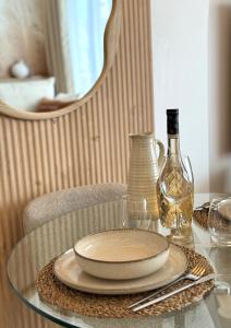 Una mesa de cristal con un plato y una botella de vino. en Sweet Home - Cocon élégant, balcon & parking privé, en Chambéry