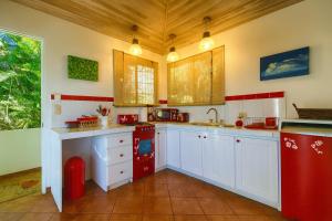 a kitchen with white cabinets and red appliances at Cottage in Magic Mountain Views in Jesus
