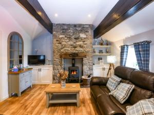 a living room with a leather couch and a stone fireplace at Cosy Cottage in Menai Bridge