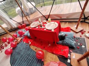 a cat sleeping under a table with a red table cloth at Sweet Forest-Domo Sol in Sanabria