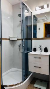 Un baño con ducha de cristal y lavabo. en Apartament Dworcowa z widokiem na park, en Kołobrzeg
