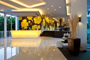 a lobby with a staircase with yellow flowers on the wall at Hotel J Pattaya - SHA Extra Plus in Pattaya Central