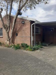 a brick building with a tree in front of it at Gracious Beauty in Bloemfontein