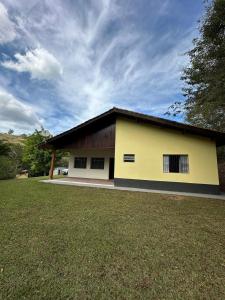 a yellow and white building with a grass yard at Chácara em Piracaia in Piracaia