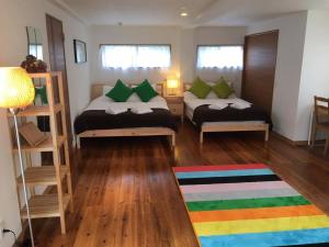 um pequeno quarto com 2 camas e um tapete colorido em The Villa Kazbo em Amami