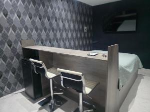 La CoyoteraにあるCataleya Suites Cassandraのベッド1台付きの客室で、デスクと椅子2脚が備わります。