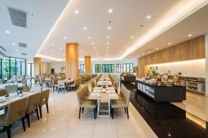een restaurant met tafels, stoelen en ramen bij Hotel J Pattaya - SHA Extra Plus in Pattaya