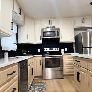a kitchen with white cabinets and stainless steel appliances at Raider Retreat-Your TTU Basecamp in Lubbock